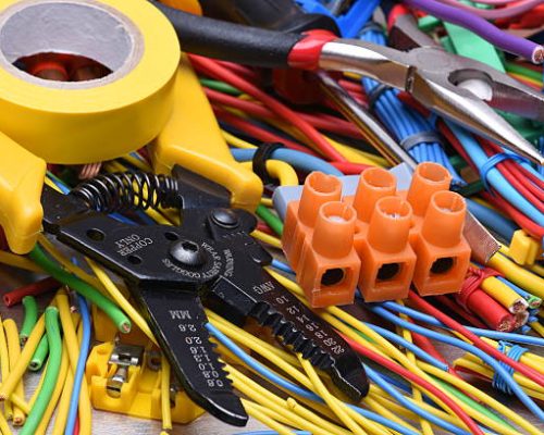 Electrical tools and cables used in electrical installations on grey metal background